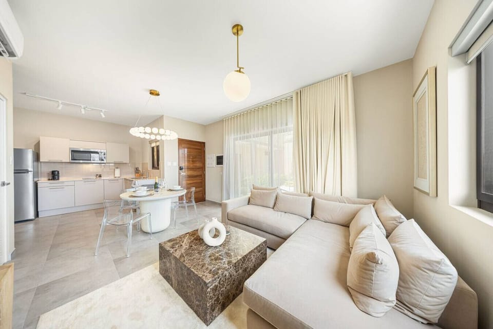 Experience modern elegance. This bright, open-concept living and dining area blends sleek neutral tones with a stunning marble coffee table. Perfect for luxurious, relaxed living.