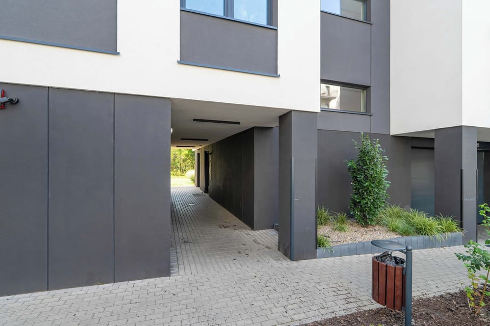 The entrance to the building leads through a modern passage with greenery and a carefully designed space.