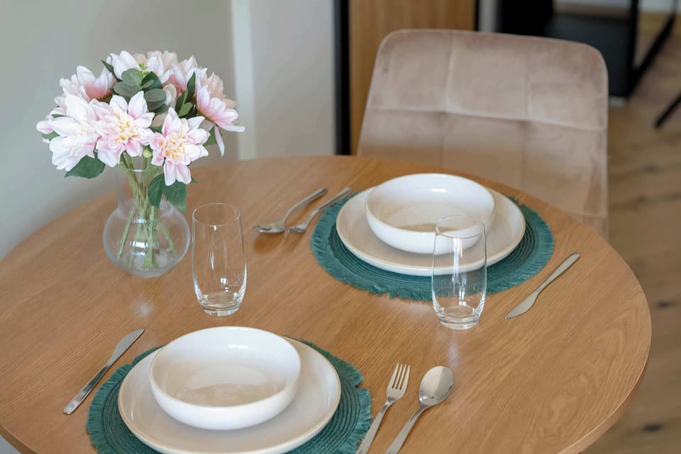 A round table set with elegant tableware and fresh flowers creates a pleasant atmosphere for shared meals.