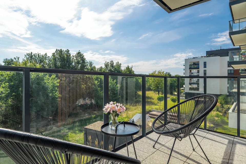 A balcony with a view of greenery and modern buildings offers the perfect spot to enjoy a morning coffee in the fresh air.