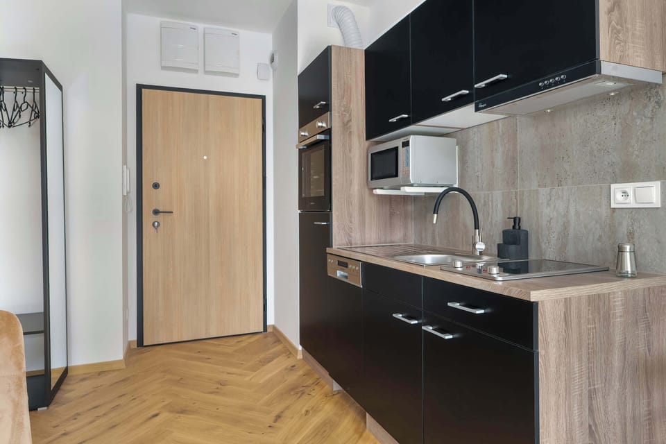An elegant hallway with natural-toned finishes leads to the kitchen, giving the apartment a cohesive character.