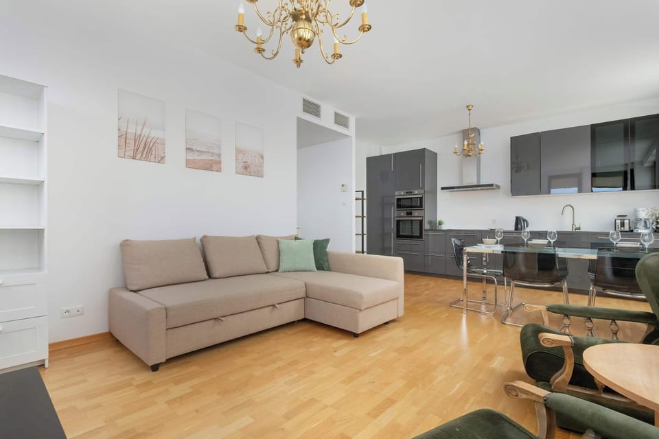 A combined living and kitchen area with a sofa and modern kitchen appliances. The space is open and well-lit, perfect for socializing and cooking.