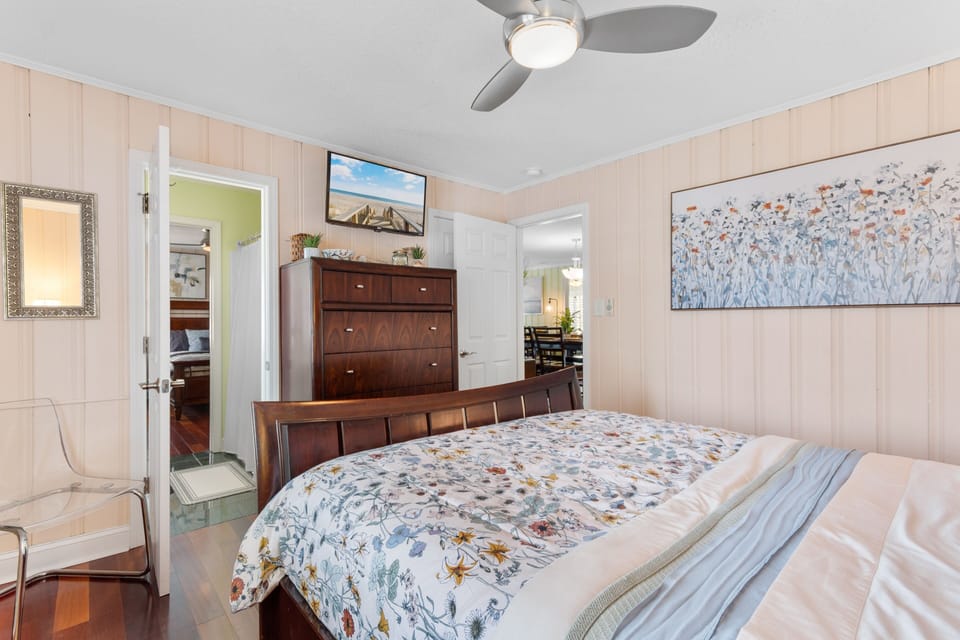 Unwind in your peaceful bedroom featuring warm wood furnishings, original artwork, and a ceiling fan for your comfort.