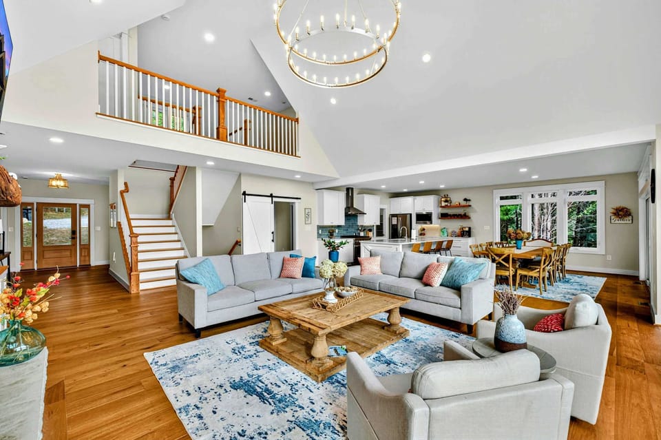 Great Room and Loft - The open living area with the upper loft railing, staircase, kitchen, dining, and barn door all visible from one vantage point.