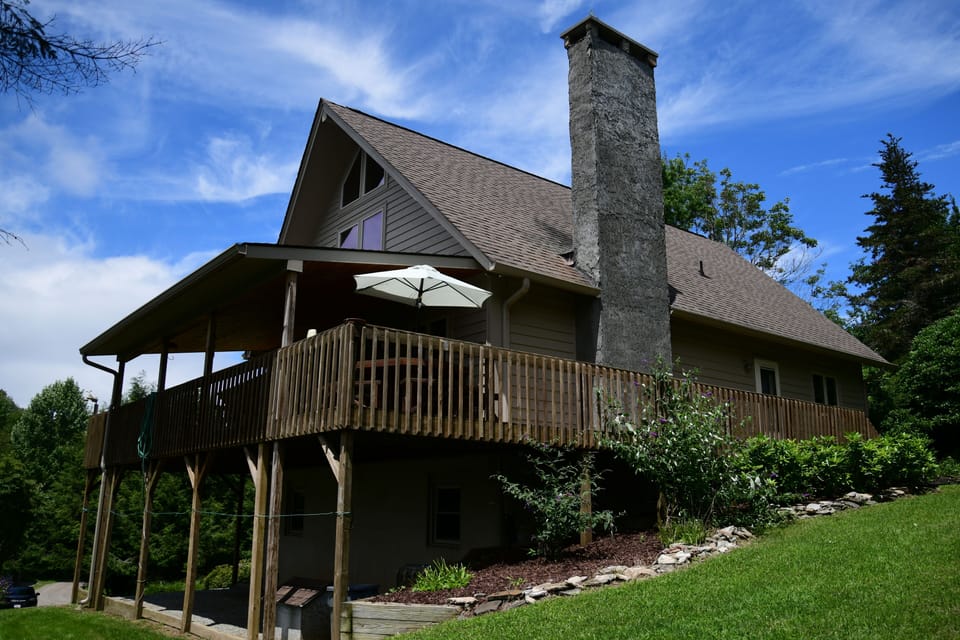 As you pull up to the home, you'll see a flight of steps up to the deck. To avoid these stairs, walk around the home to the right side yard with the chimney and walk onto the deck.