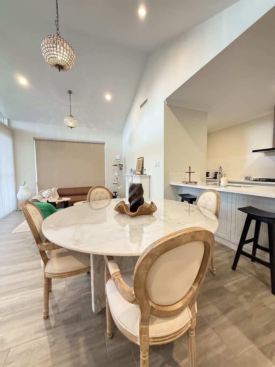 Chic open-concept living! Enjoy a spacious dining area with a stylish table and elegant vase, seamlessly flowing into a modern kitchen with sleek countertops and a convenient sink. Perfect for entertaining and relaxing.