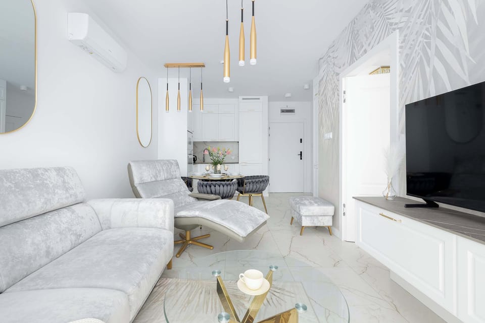 A stylish lounge area featuring a soft sofa and wall-mounted TV. Golden accents add a touch of elegance.