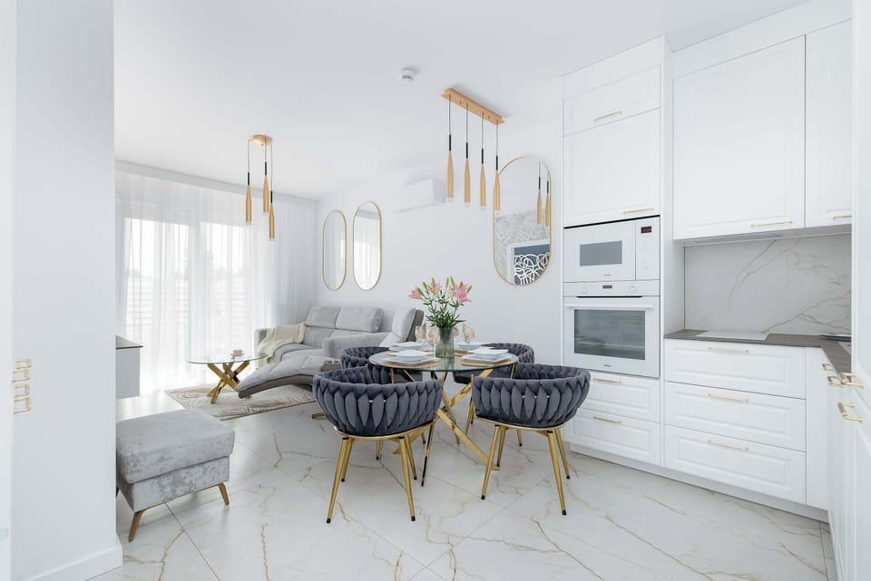 A modern dining area with a round table and plush chairs. The space is illuminated by golden pendant lamps.