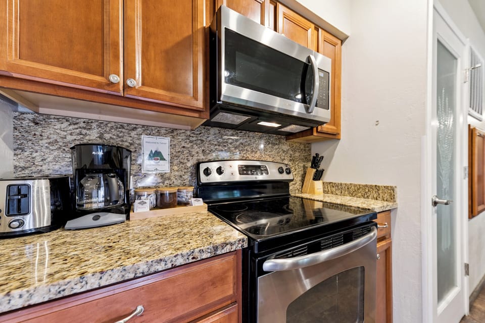 The kitchen is fully equipped with modern appliances, including coffee maker, toaster, microwave, oven, and stove.