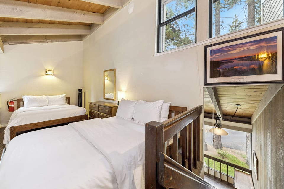 Rest peacefully in your cozy loft bedroom with rustic wood beams and lake views through expansive windows.
