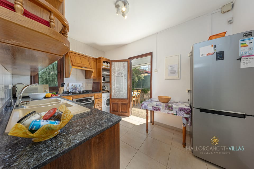 Fully equipped and bright kitchen at Casa Luna, Puerto de Alcudia. Features granite countertops, oven, dishwasher, washing machine and full appliances, with direct access to the outdoor terrace for comfortable al fresco dining.