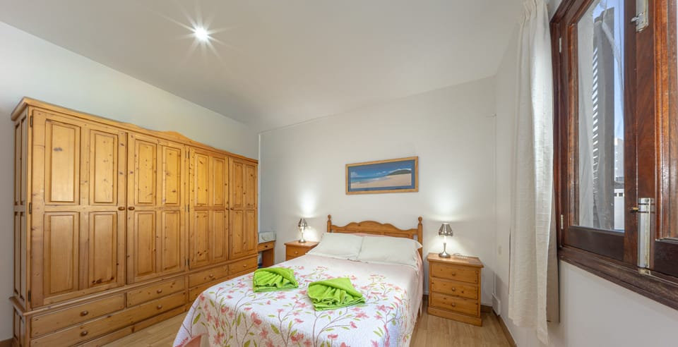 Spacious and bright master bedroom featuring a double bed, large built-in wardrobe and natural light, perfect for a comfortable stay in Puerto Alcudia.