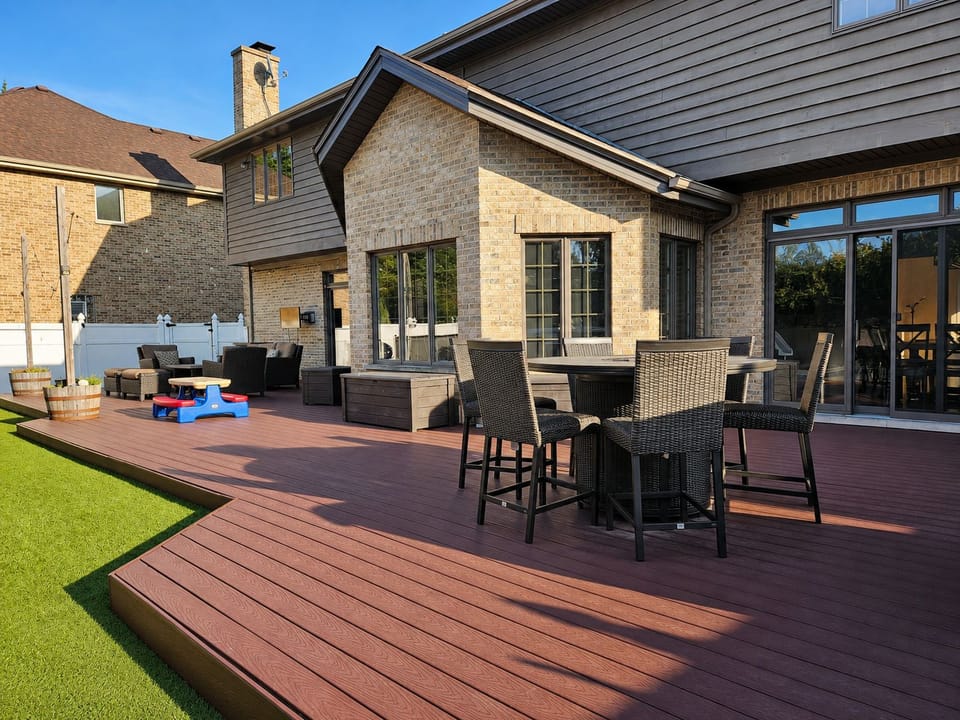 Spacious backyard deck with outdoor dining, lounge seating, and sunny lawn