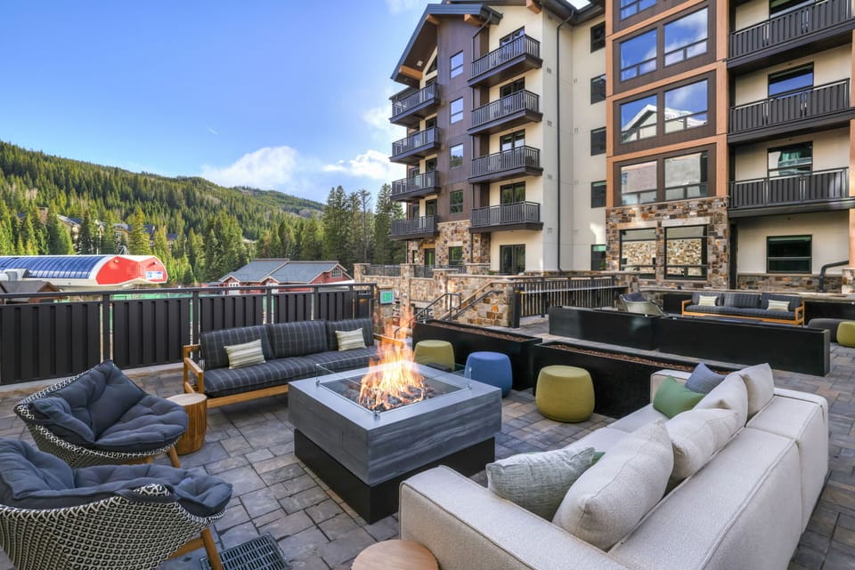 Outdoor lounge area with a fire pit and views of surrounding forest.