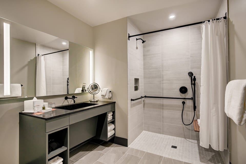 Roll-in shower with grab bars, handheld head, and textured floor — a bathroom that feels confident, not compromised