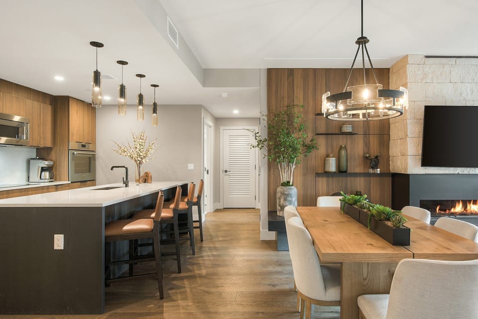 Kitchen and bar area with island seating, open shelving, and decorative plants nearby.