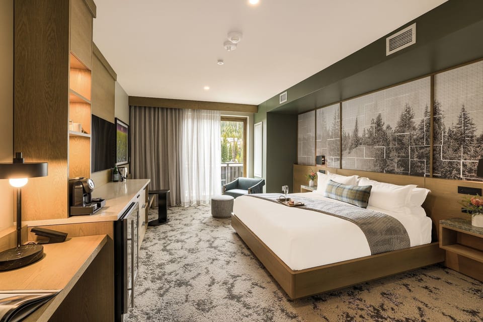 King bed and green armchair with sheer curtains opening to the balcony — fresh mountain air one step away