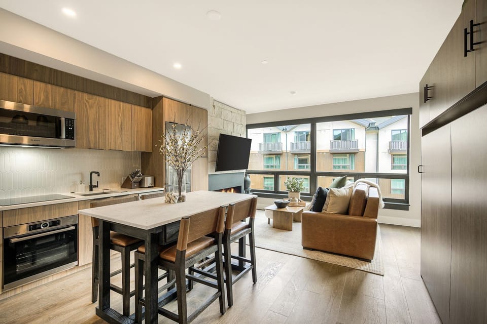 Stone accent wall with flat-screen TV connecting to the kitchen — perfect for movie nights and lazy resort mornings