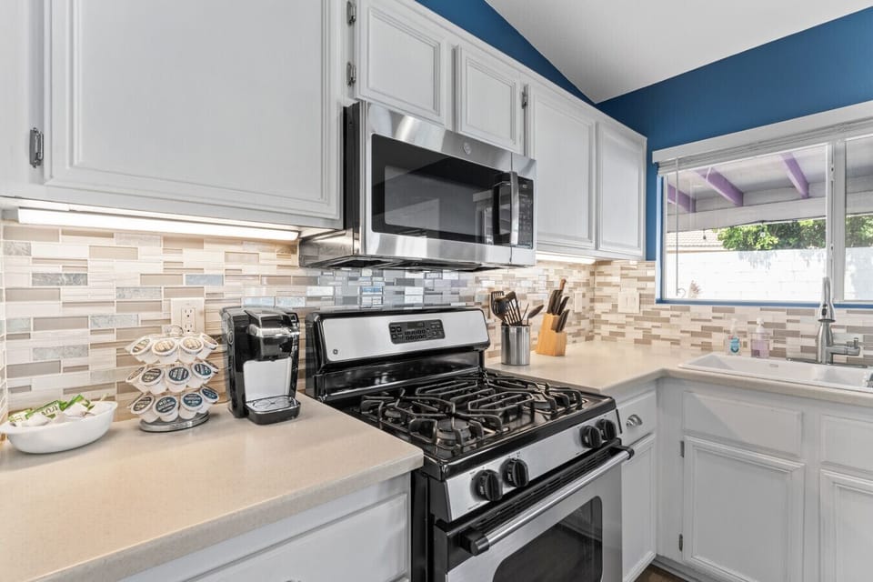 Modern kitchen setup w/ gas range, tiled backsplash & coffee station ready to go.