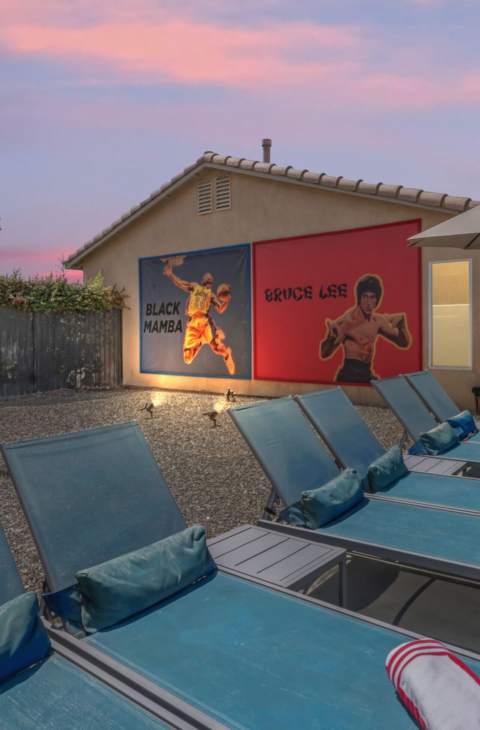Mural wall featuring Black Mamba & Bruce Lee beside poolside loungers.