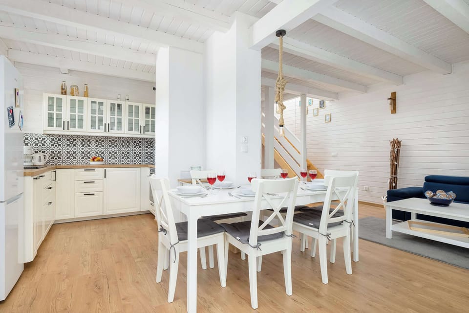 A dining room with a long wooden table and white chairs under a slanted ceiling.