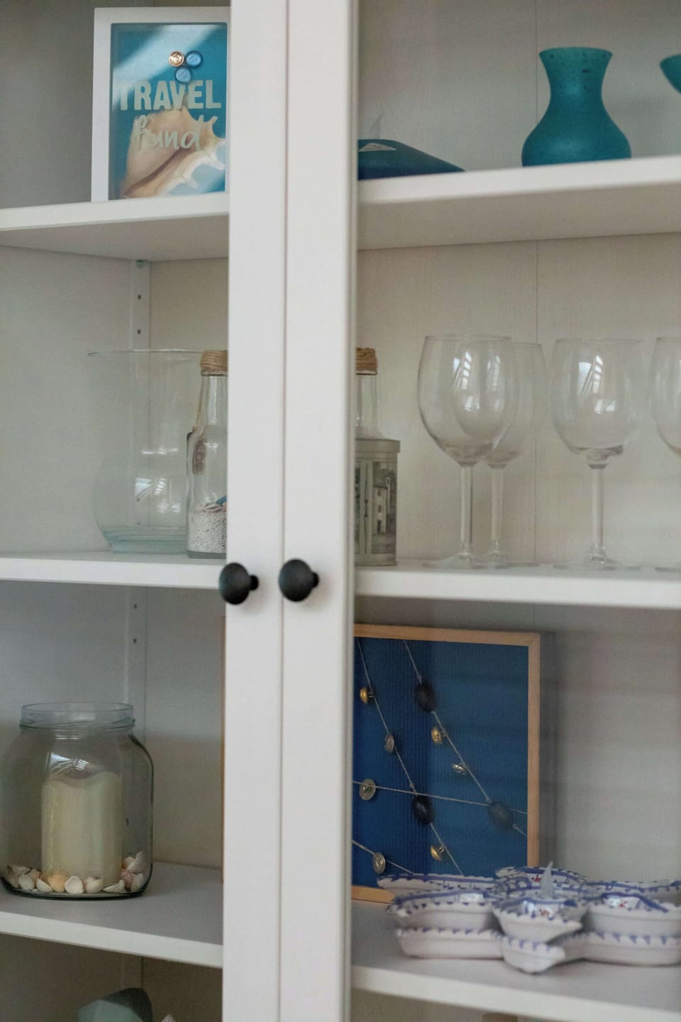 A small shelving unit with glassware and decorative accents.