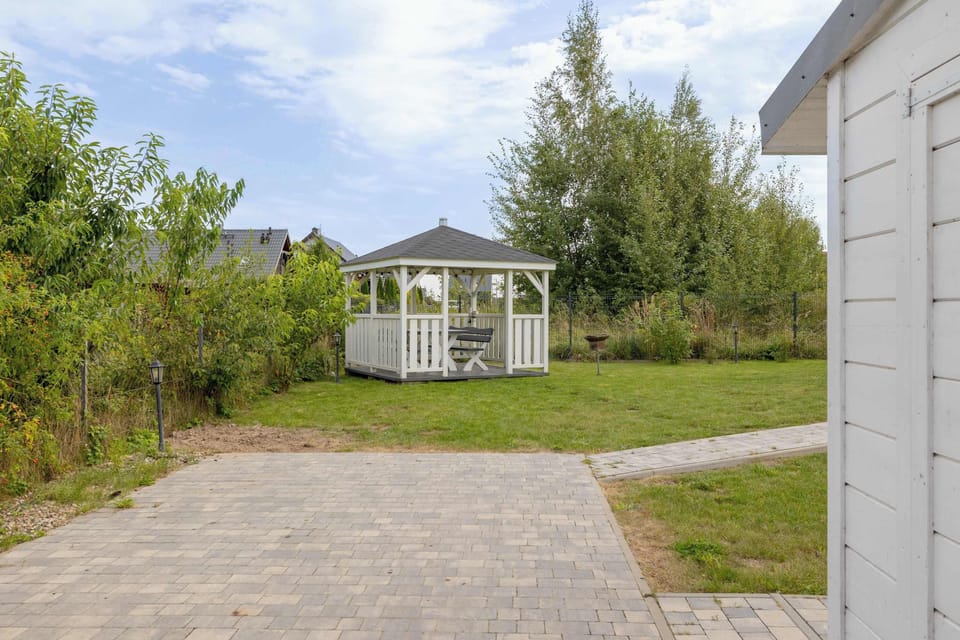 A paved pathway leading to the cottage. Greenery surrounds the house, creating a private setting.