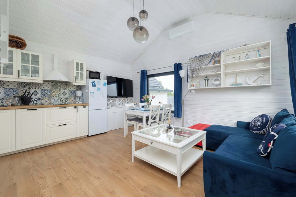 Another angle of the living room featuring a blue sofa, white coffee table, and a TV. Open shelving adds storage and decoration.