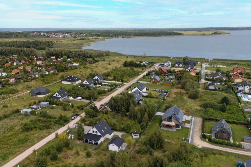 A wide view of the neighborhood showing several cottages and open fields. The coastline can be seen in the distance.