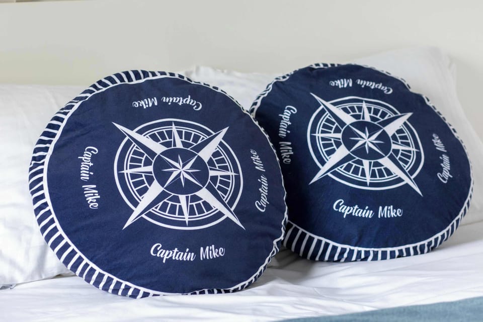 A pair of round blue cushions decorated with a compass rose design. Nautical-themed accessories add character to the cottage.