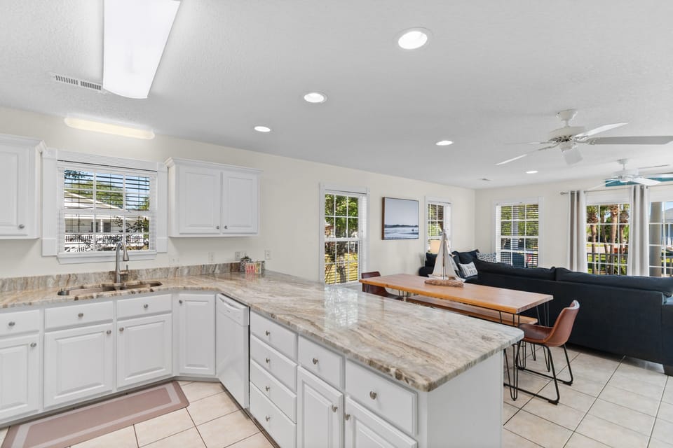 Prepare meals in your spacious open kitchen featuring granite countertops and white cabinets, seamlessly flowing into the comfortable living area.