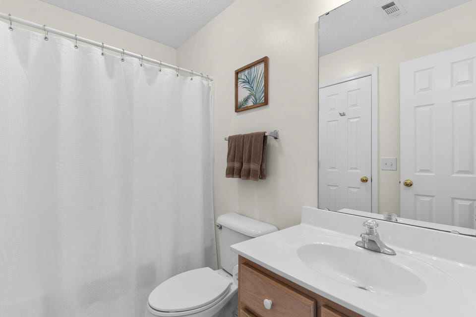 Step into your private bathroom sanctuary with a refreshing tub-shower combo, crisp linens, and coastal-inspired artwork welcoming you home.