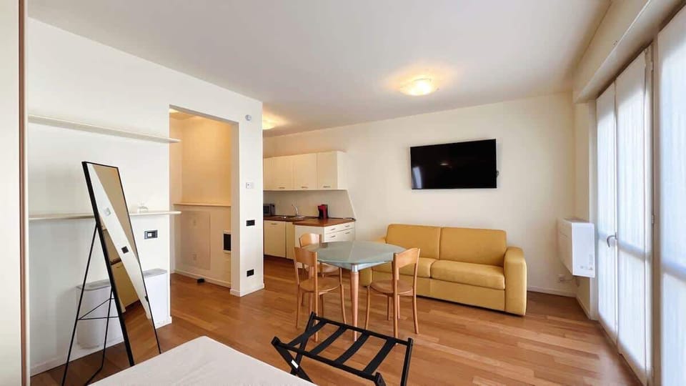 Bright open-plan living room with central dining table, comfortable sofa and wall-mounted TV