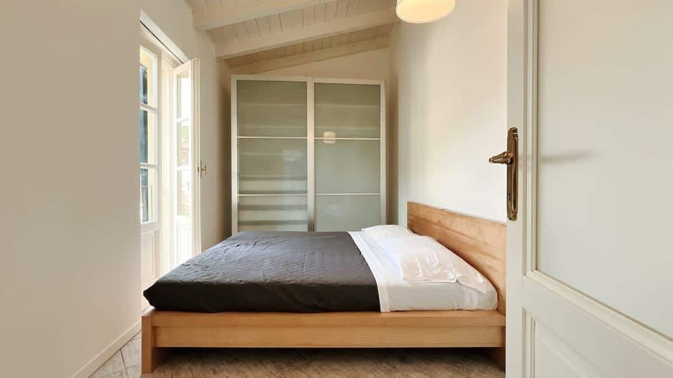 Bright and modern double bedroom featuring a large wardrobe and a French door that fills the space with natural light