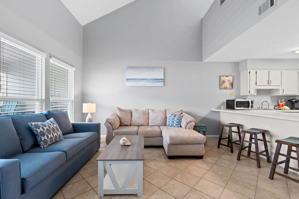 The living room offers a spacious and inviting retreat with plenty of comfortable seating, perfect for relaxing after a day at the beach.