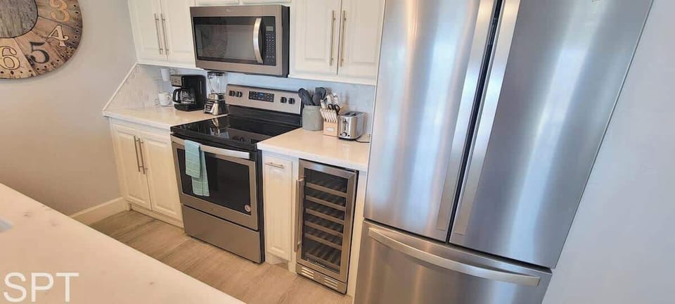 Bright open kitchen with marble island, stainless appliances, and a stylish dining nook — a modern, inviting space perfect for cooking and gathering.