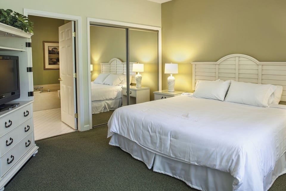 Unwind in crisp linens with calming lamps and quiet comfort.