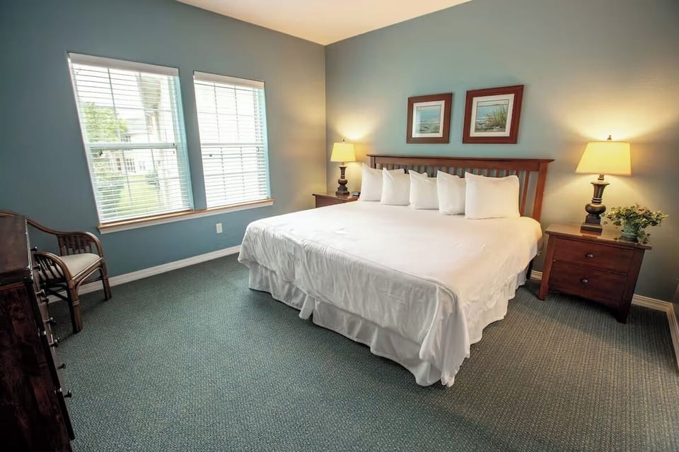 Settle into a serene bedroom with bright windows and lamps.