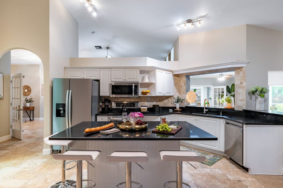 Updated kitchen with white cabinetry and stone counters.