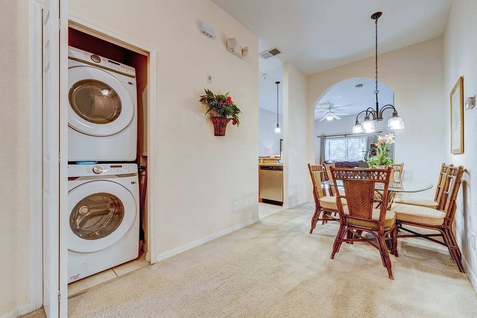 Dining area with rattan chairs and a stacked washer and dryer for convenience.