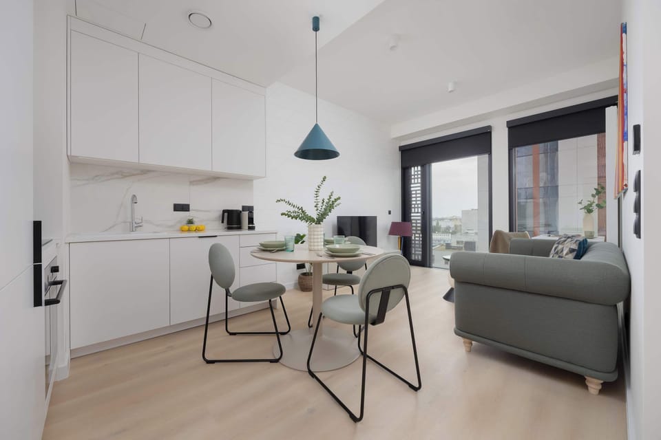 A spacious open-plan living area combining kitchen, dining, and lounge. Neutral tones and minimalist furniture create a calm environment.