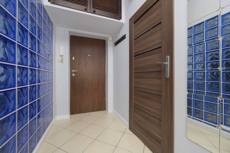 The hallway with a striking wall of blue glass blocks and wooden doors adds a modern touch and creates harmony with the rest of the apartment.