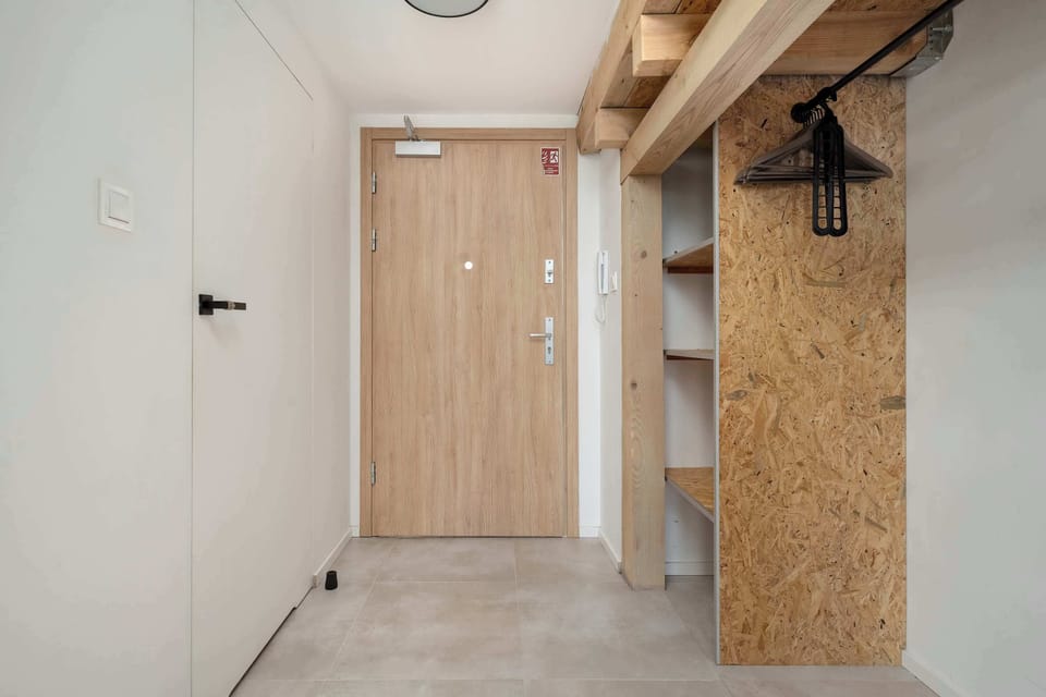 An entryway with wooden paneling, industrial details, and hooks for coats.