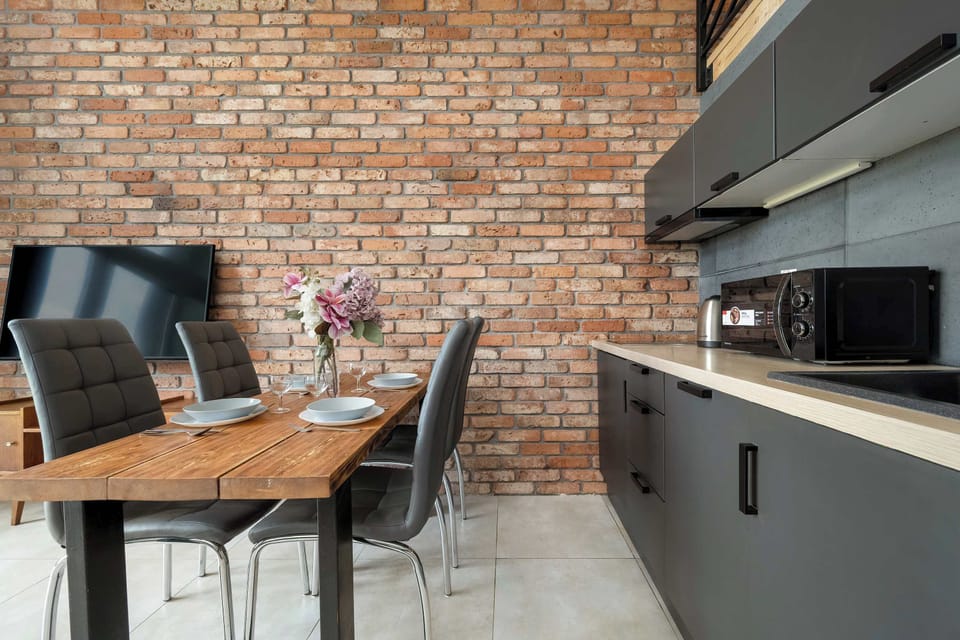 A dining table set with plates and flowers, next to a brick accent wall.