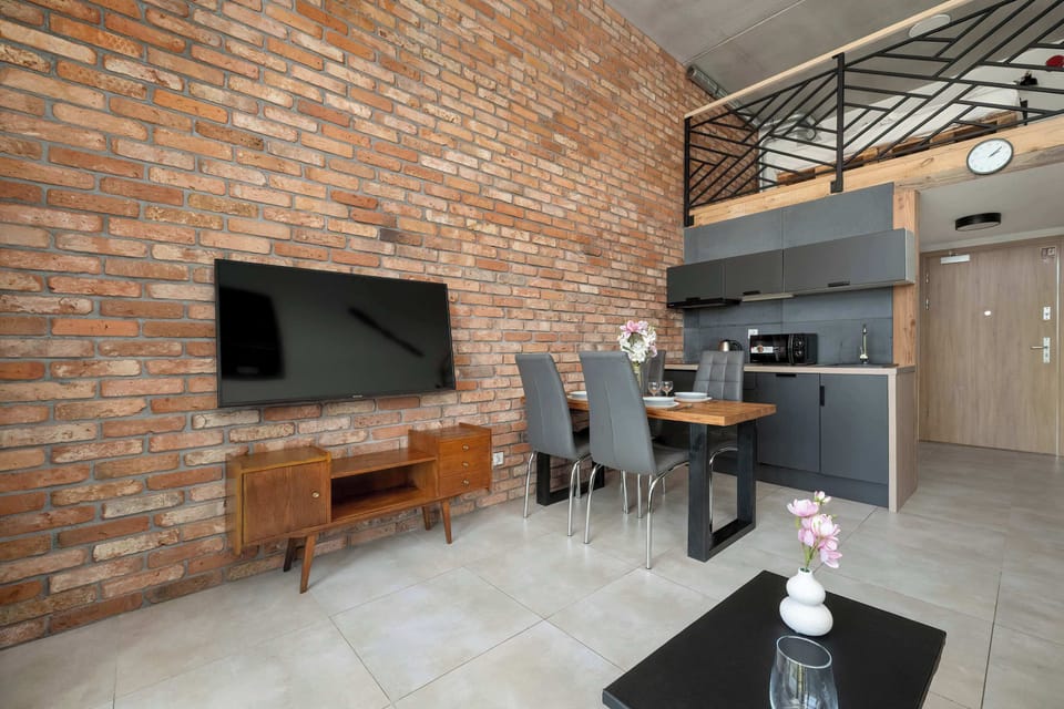 A living room corner with a TV mounted on a brick wall and open space below.