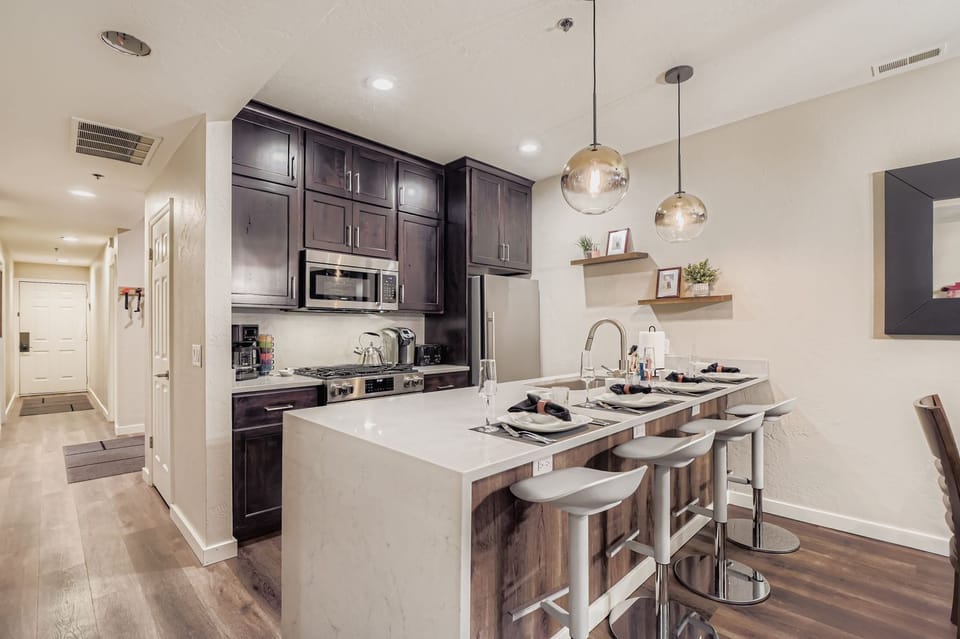 Modern kitchen with quartz island, bar seating, and stainless steel appliances. Perfect for cooking meals during your stay.