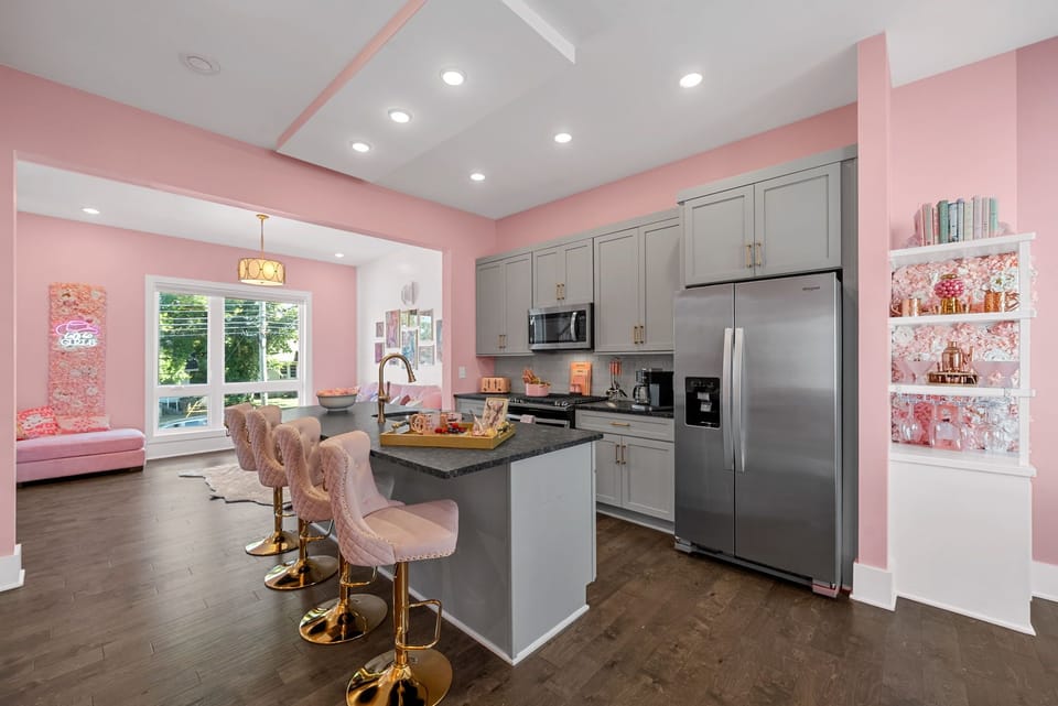 Playful pink kitchen with matching utensils and barstools—fun and vibrant