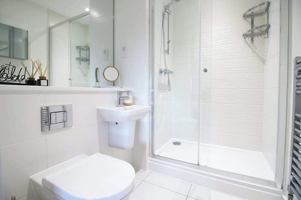 A sleek, modern en-suite featuring a spacious walk-in glass shower, contemporary tiling, and a stylish sink area—perfect for refreshing mornings and relaxing evenings.