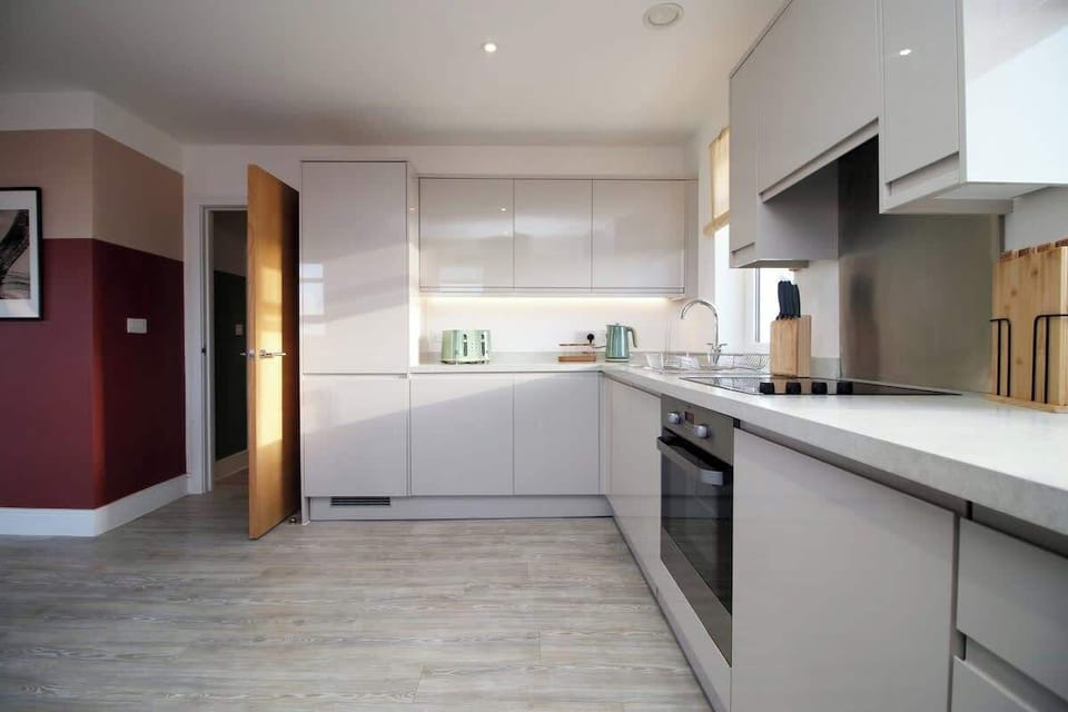 A sleek, fully equipped kitchen with contemporary units, generous worktop space, and integrated appliances, offering everything needed for convenient and enjoyable self-catering stays.