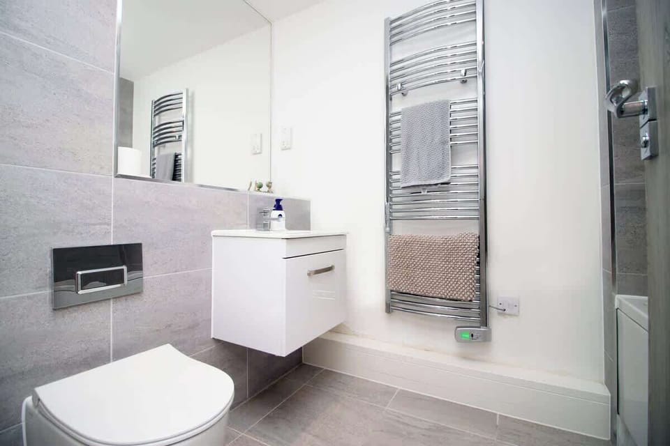 Beautifully finished with a modern vanity, large mirror, and heated towel rail, this bright bathroom offers a clean, luxurious space to refresh and unwind.